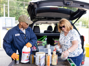 Household Hazardous Waste Collection Facility staff helping customer identify chemicals, person unloading vehicle with chemicals